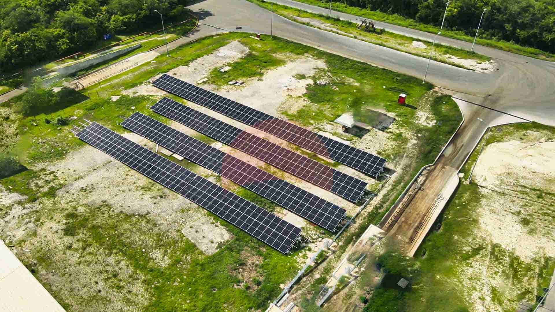 drone view of four arrays of solar panels, over green grass
